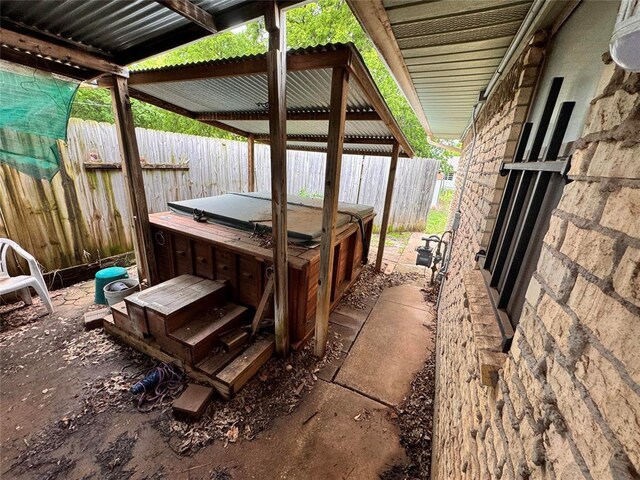 view of patio / terrace with a hot tub and fence