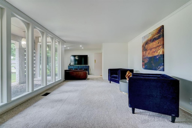 living area featuring carpet flooring, baseboards, visible vents, and ornamental molding