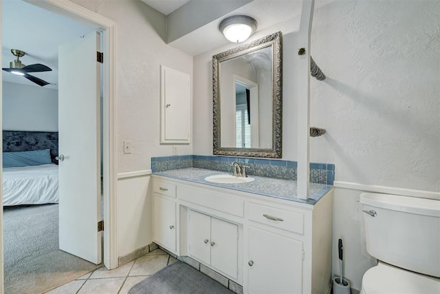 bathroom featuring connected bathroom, tile patterned flooring, vanity, toilet, and a ceiling fan