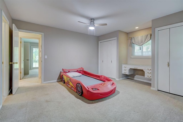 carpeted bedroom featuring two closets, baseboards, multiple windows, and built in study area