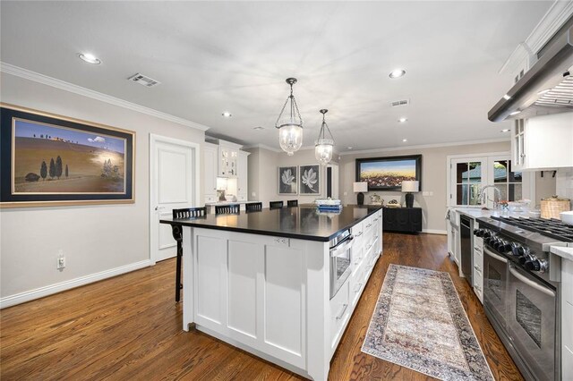 1119 Glenwood Ave, Nichols Hills, OK 73116 - kitchen with ventilation hood, white cabinetry, a kitchen island, dark countertops, and appliances with stainless steel finishes