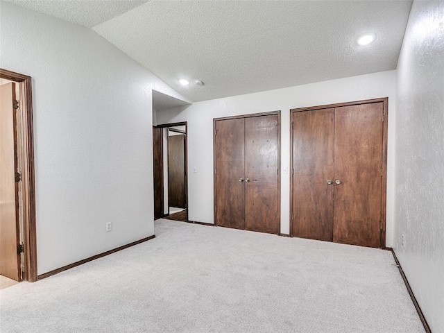 1357 W Cedarbrook Ln, Moore, OK 73170 - unfurnished bedroom featuring a textured ceiling, multiple closets, vaulted ceiling, and carpet