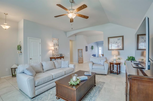 living area with ceiling fan, arched walkways, baseboards, light tile patterned floors, and vaulted ceiling