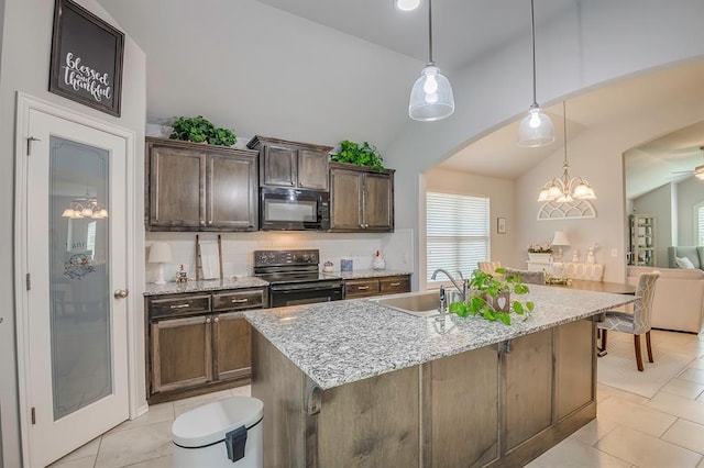 kitchen featuring arched walkways, a sink, light tile patterned floors, black appliances, and lofted ceiling
