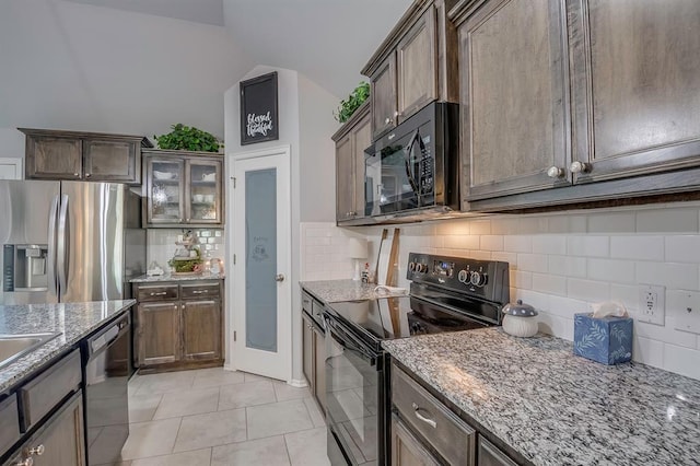 kitchen with light stone counters, black appliances, vaulted ceiling, and tasteful backsplash