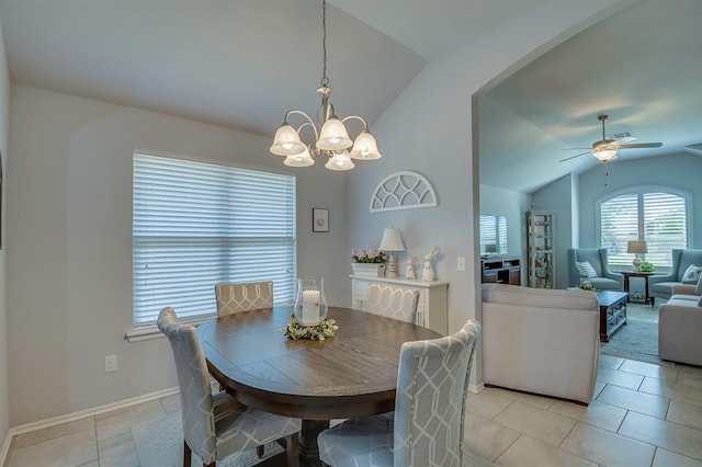 dining space with light tile patterned flooring, arched walkways, lofted ceiling, and ceiling fan with notable chandelier