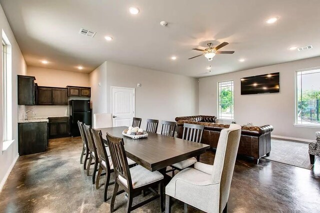 dining room featuring concrete floors, visible vents, a ceiling fan, and baseboards