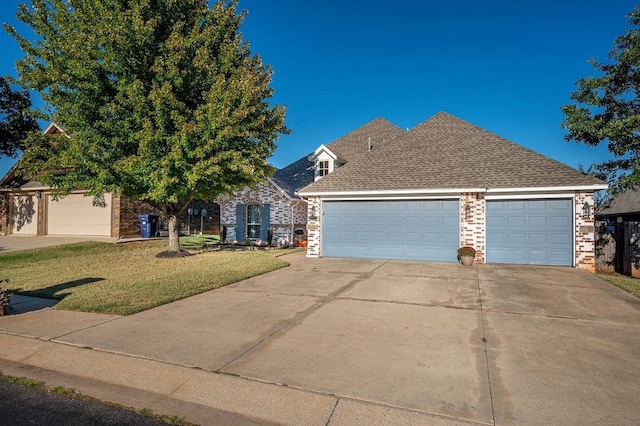 view of front of property featuring a garage, a front lawn, roof with shingles, brick siding, and concrete driveway