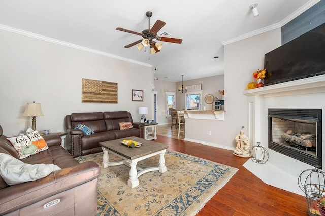 living area with baseboards, ornamental molding, a ceiling fan, and wood finished floors