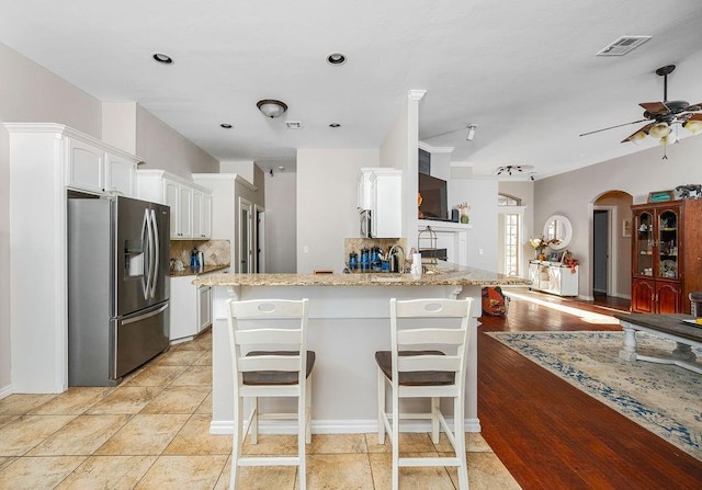 kitchen featuring white cabinets, ceiling fan, appliances with stainless steel finishes, decorative backsplash, and visible vents