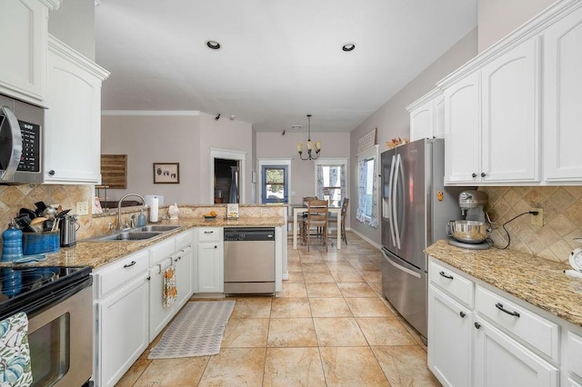 kitchen featuring a sink, appliances with stainless steel finishes, backsplash, and a notable chandelier