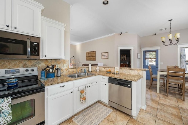 kitchen with a peninsula, white cabinetry, a chandelier, a sink, and stainless steel appliances