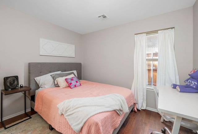 bedroom featuring visible vents, baseboards, and wood finished floors