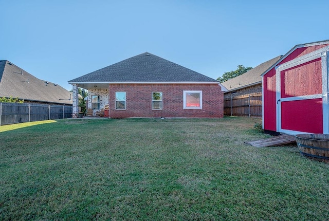 rear view of house featuring a storage shed, an outbuilding, a yard, and a fenced backyard