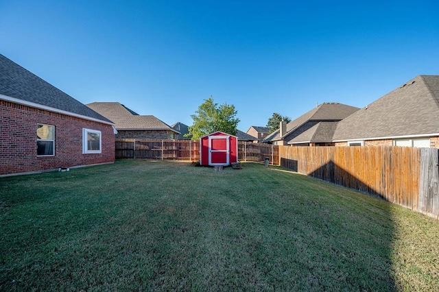 view of yard featuring an outdoor structure, a fenced backyard, and a storage unit