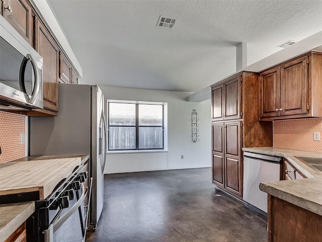 1621 Park View Pl, Edmond, OK 73003 - kitchen featuring appliances with stainless steel finishes, finished concrete flooring, light countertops, tasteful backsplash, and visible vents