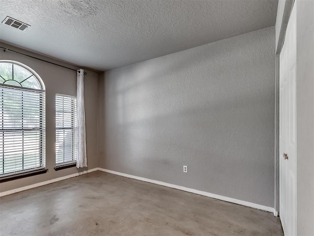 1621 Park View Pl, Edmond, OK 73003 - spare room with a textured wall, concrete floors, a textured ceiling, and visible vents