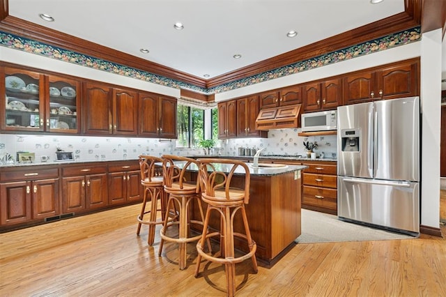 4200 Oakdale Farm Cir, Edmond, OK 73013 - kitchen with white microwave, ornamental molding, stainless steel fridge with ice dispenser, and custom range hood