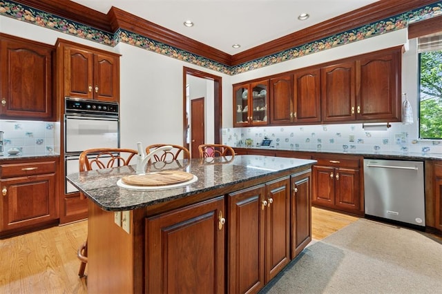 4200 Oakdale Farm Cir, Edmond, OK 73013 - kitchen featuring dark stone counters, double oven, dishwasher, light wood-style floors, and a kitchen island