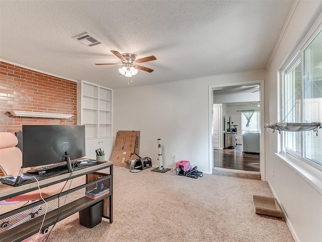 carpeted office space with a textured ceiling, built in features, a ceiling fan, baseboards, and visible vents