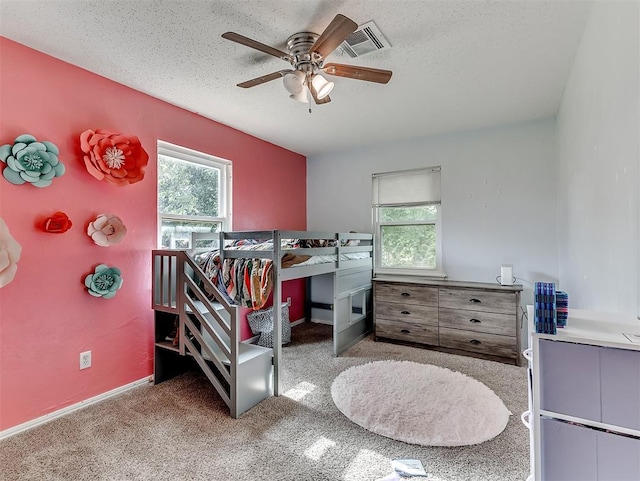 carpeted bedroom featuring baseboards, visible vents, multiple windows, and ceiling fan