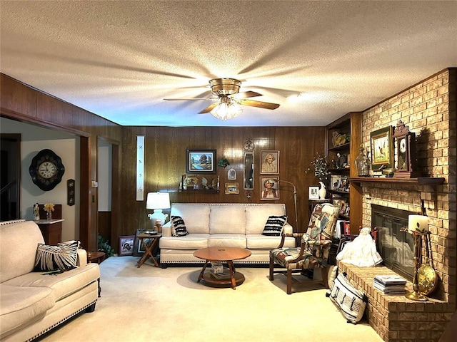carpeted living area with a textured ceiling, a brick fireplace, ceiling fan, and wooden walls