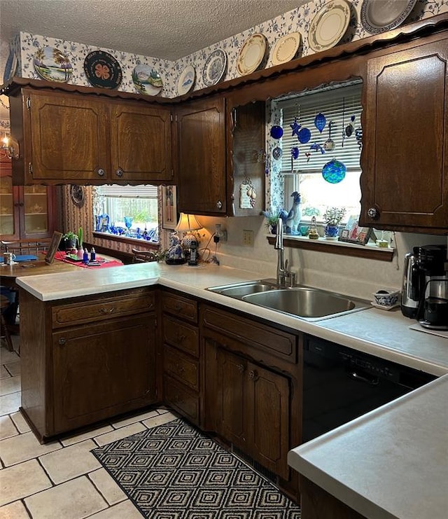 kitchen with a peninsula, dark brown cabinets, light countertops, a textured ceiling, and a sink