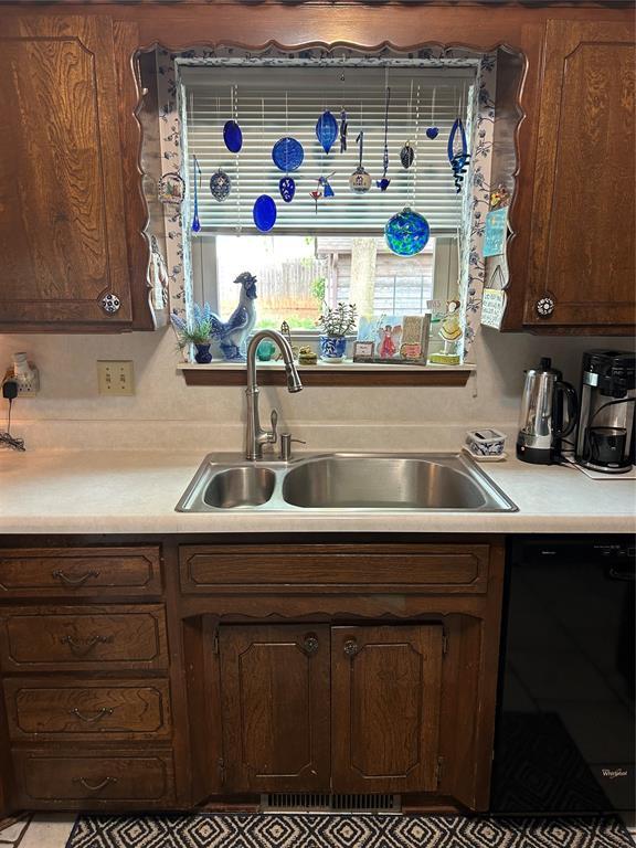 kitchen featuring a sink, black dishwasher, and light countertops