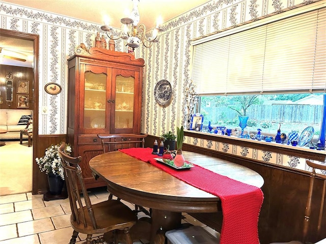 dining area with wainscoting, wallpapered walls, light tile patterned flooring, and a notable chandelier