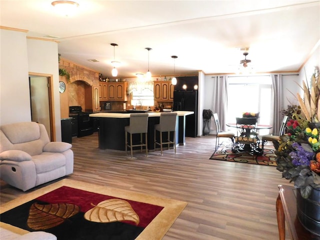 living room with ornamental molding, light wood finished floors, and arched walkways