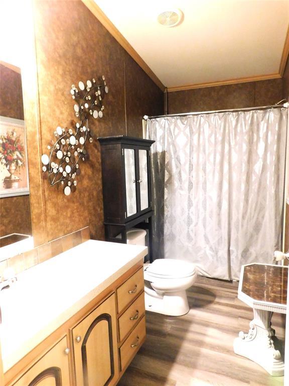 full bathroom with ornamental molding, vanity, toilet, and wood finished floors