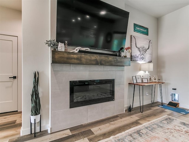 living area featuring baseboards, a fireplace, and wood finished floors