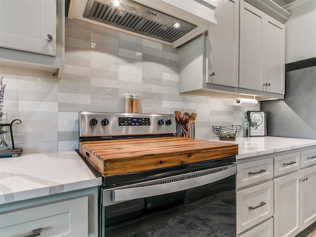 kitchen with backsplash, electric range, light stone countertops, premium range hood, and white cabinets