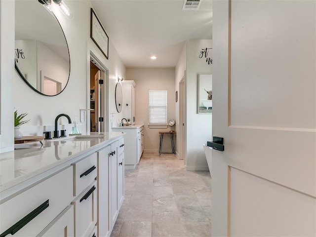 full bathroom with baseboards, visible vents, two vanities, and a sink