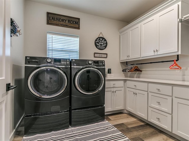 laundry room with cabinet space, wood finished floors, and washing machine and clothes dryer