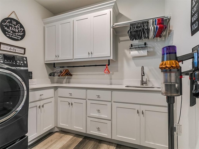 washroom featuring a sink, cabinet space, washer / clothes dryer, and wood finished floors
