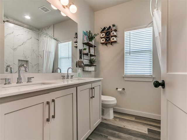 bathroom with toilet, visible vents, a sink, and wood finished floors