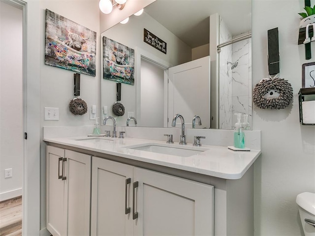 full bath with a sink, toilet, double vanity, and wood finished floors