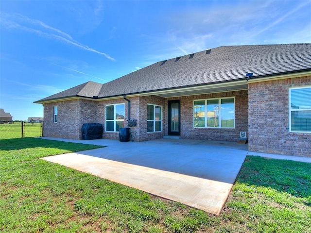 back of house with a yard, a patio, fence, and brick siding