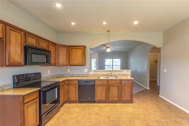kitchen featuring a sink, arched walkways, brown cabinetry, a peninsula, and black appliances
