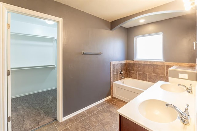 full bathroom featuring baseboards, a sink, a bath, and double vanity