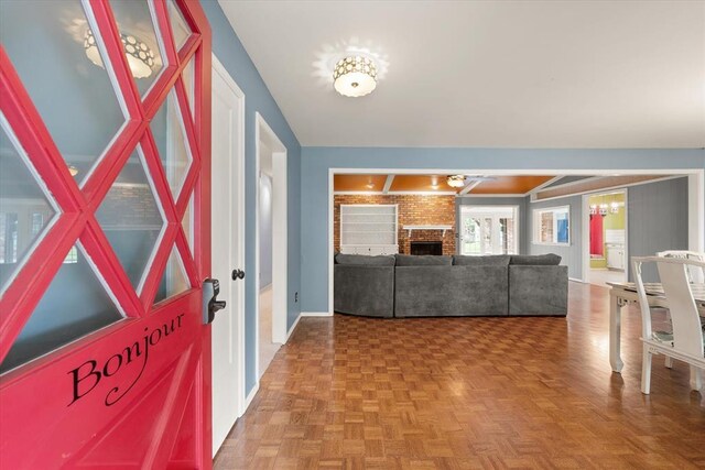 foyer featuring baseboards, a brick fireplace, and an inviting chandelier