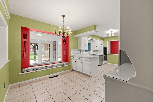 kitchen with visible vents, light countertops, white cabinets, a sink, and a notable chandelier