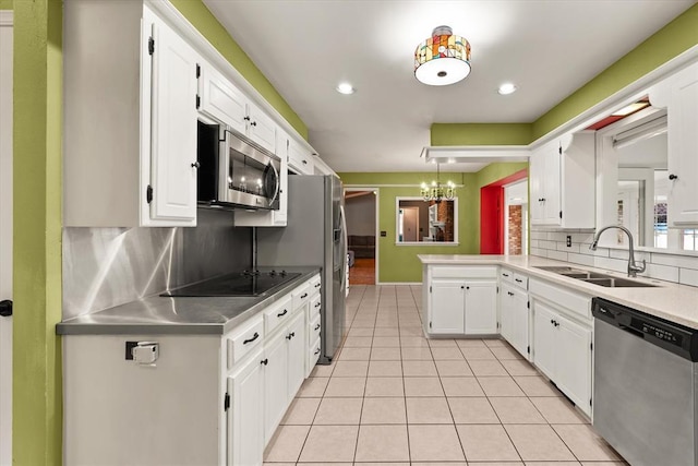 kitchen with a sink, stainless steel appliances, white cabinetry, light tile patterned floors, and tasteful backsplash