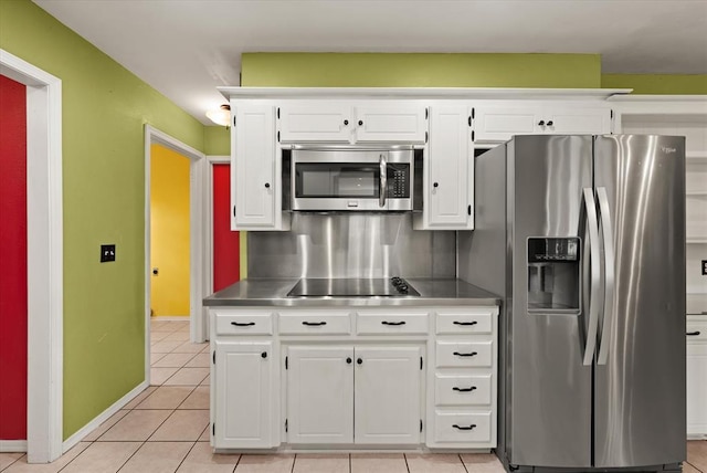 kitchen with baseboards, stainless steel countertops, white cabinets, and stainless steel appliances