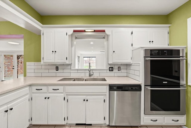kitchen with decorative backsplash, a sink, light countertops, stainless steel appliances, and white cabinetry
