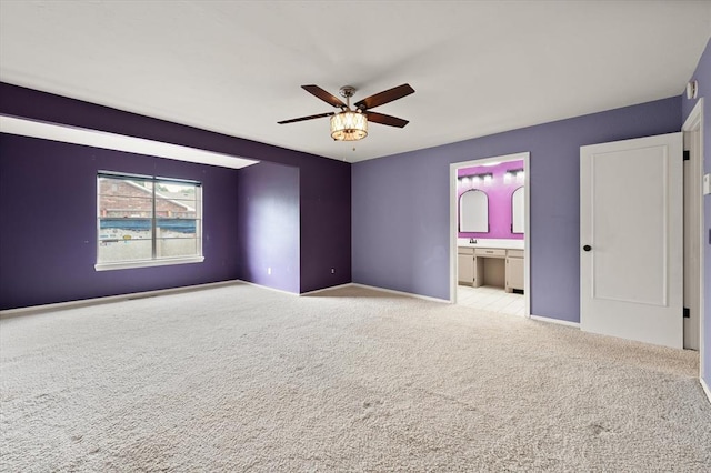 unfurnished bedroom featuring baseboards, ensuite bathroom, carpet, and ceiling fan