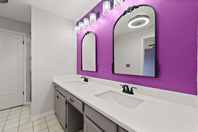 bathroom with tile patterned flooring, a sink, baseboards, and double vanity