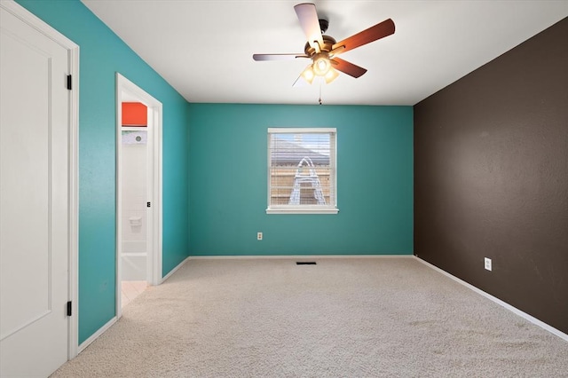 spare room with carpet floors, ceiling fan, baseboards, and visible vents