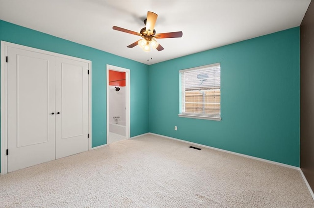 unfurnished bedroom with carpet floors, baseboards, ensuite bath, and a closet